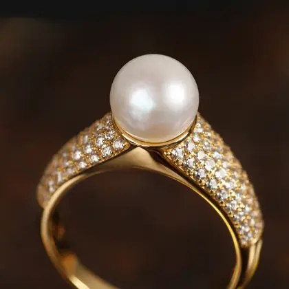 Detalhe de anel dourado com pérola e cravação pavé